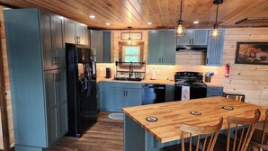 A kitchen with blue cabinets, a wooden island with chairs, and a stove.