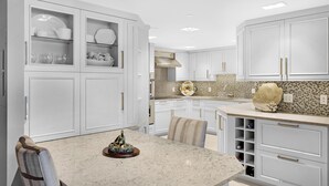 A modern kitchen with white cabinetry, a granite countertop, and a decorative island. - An Ocean Serenity at the Truman Annex in Key West (Key West)