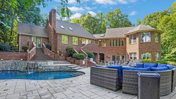Une grande maison en briques avec une piscine et un espace extérieur aménagé pour se détendre.