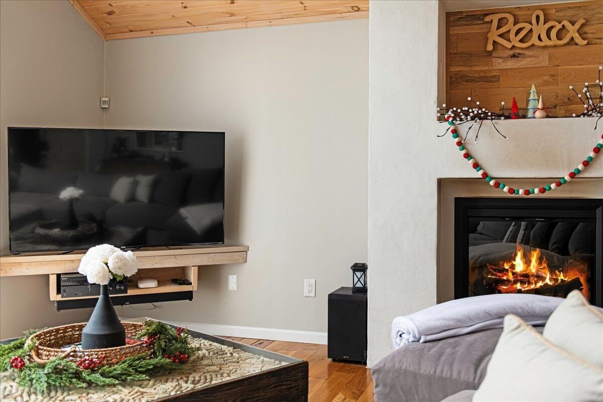 A living room with a flat-screen TV, a fireplace, and a cozy seating area.