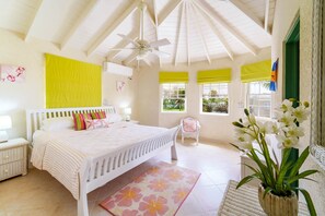 A bright bedroom with a white bed, a ceiling fan, and a view of greenery outside. - Ocean View by Bluescape (Belair)