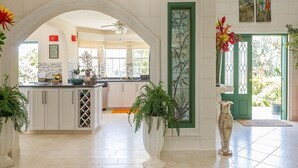 A spacious kitchen with white cabinets, a central island, and a green door. - Ocean View by Bluescape (Belair)