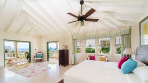 A spacious bedroom with a large bed, a ceiling fan, and a view of the ocean through a balcony door. - Ocean View by Bluescape (Belair)