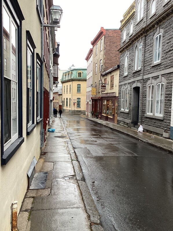 A narrow street lined with historic buildings, including a bakery and a shop with a sign that reads "La Cantina." - Historic Old Quebec. One-bedroom apartment. Sleeping arrangements for 4. Parking space. (Québec)