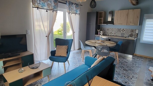 A modern living room with a blue sofa, a wooden coffee table, and a TV. - The Blue Tit (Ognes)