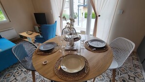 A dining area with a round wooden table set for four, surrounded by blue chairs. - The Blue Tit (Ognes)