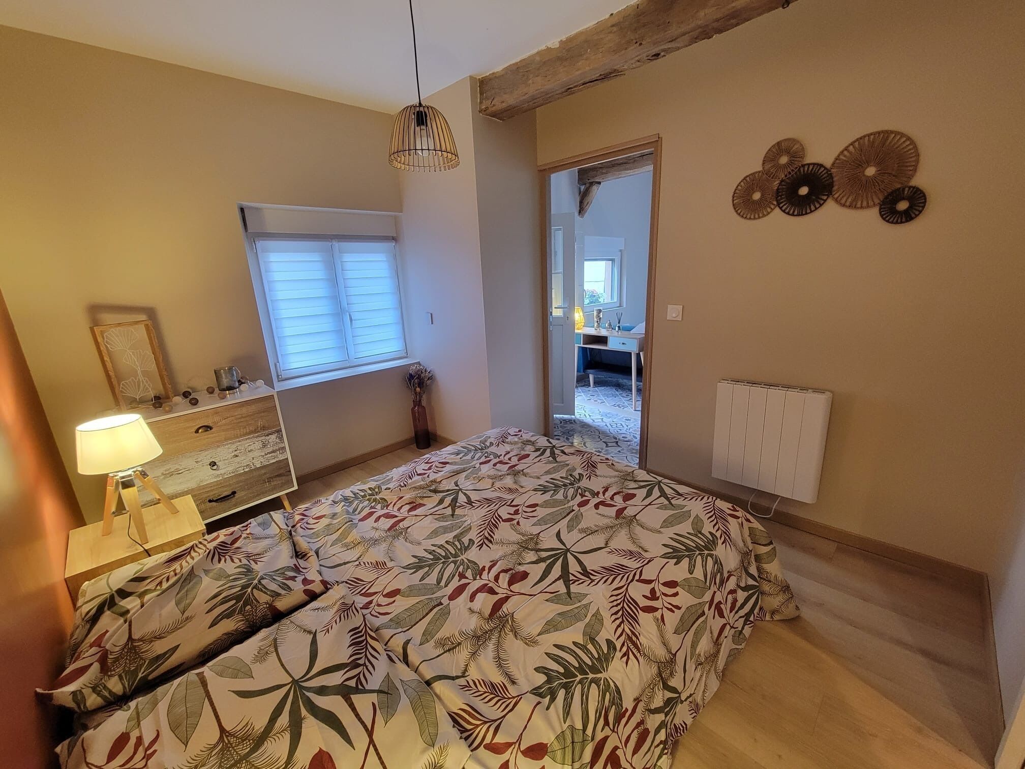A bedroom with a bed, a dresser, a lamp, a window, and a radiator.
