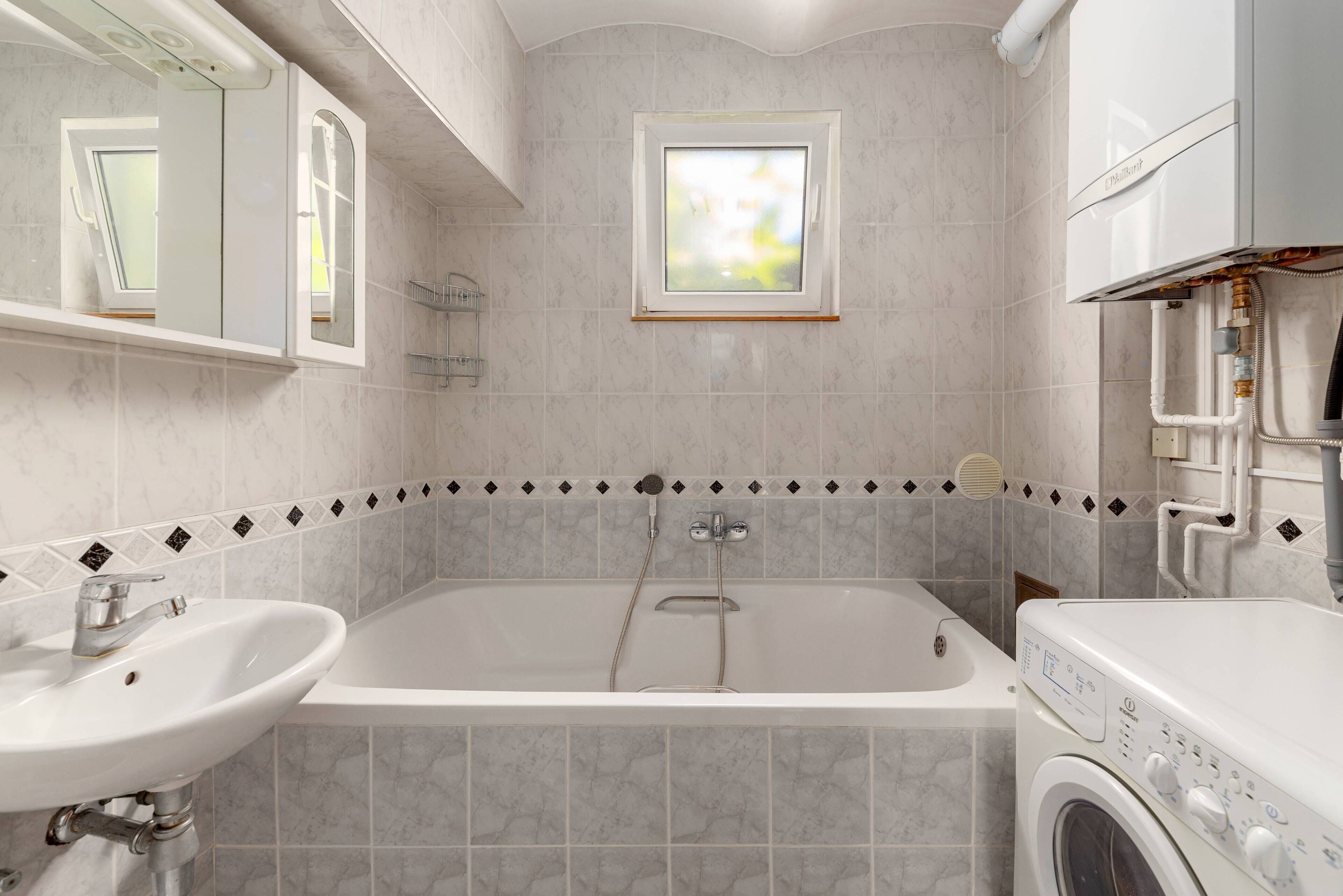 A bathroom with a bathtub, a sink, and a washing machine.