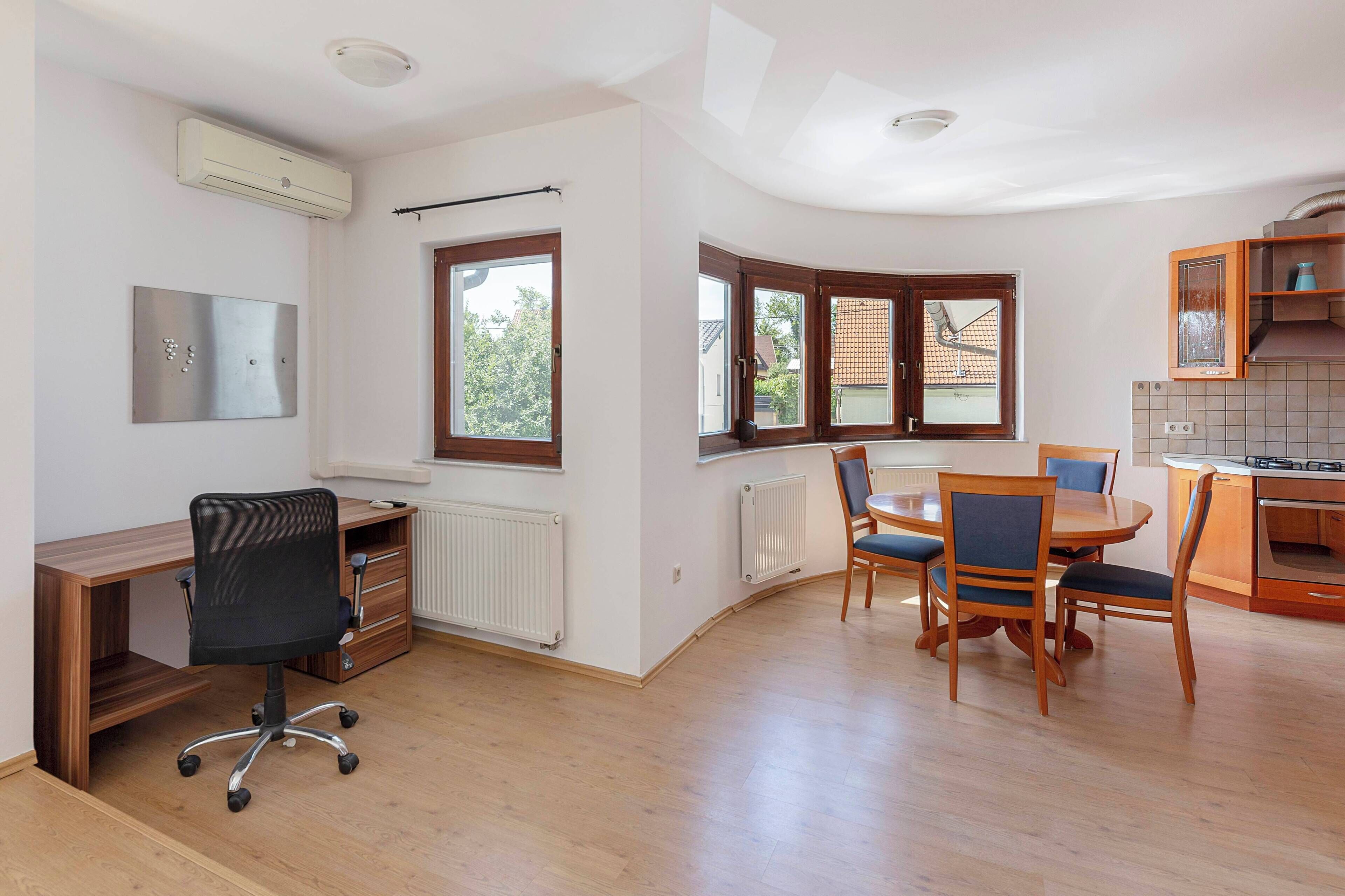 A modern kitchen with wooden cabinets, a dining table with chairs, and a built-in oven.