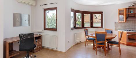 A modern kitchen with wooden cabinets, a dining table with chairs, and a built-in oven.