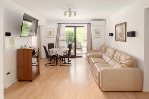 コンフォート アパートメント ガーデンビュー | リビング エリア | 90 インチのスマートテレビ (デジタル放送視聴可)、Netflix、DVD プレーヤー