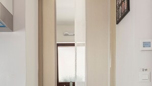 A narrow hallway leading to a bathroom with a window, a sink, and a towel rack.
