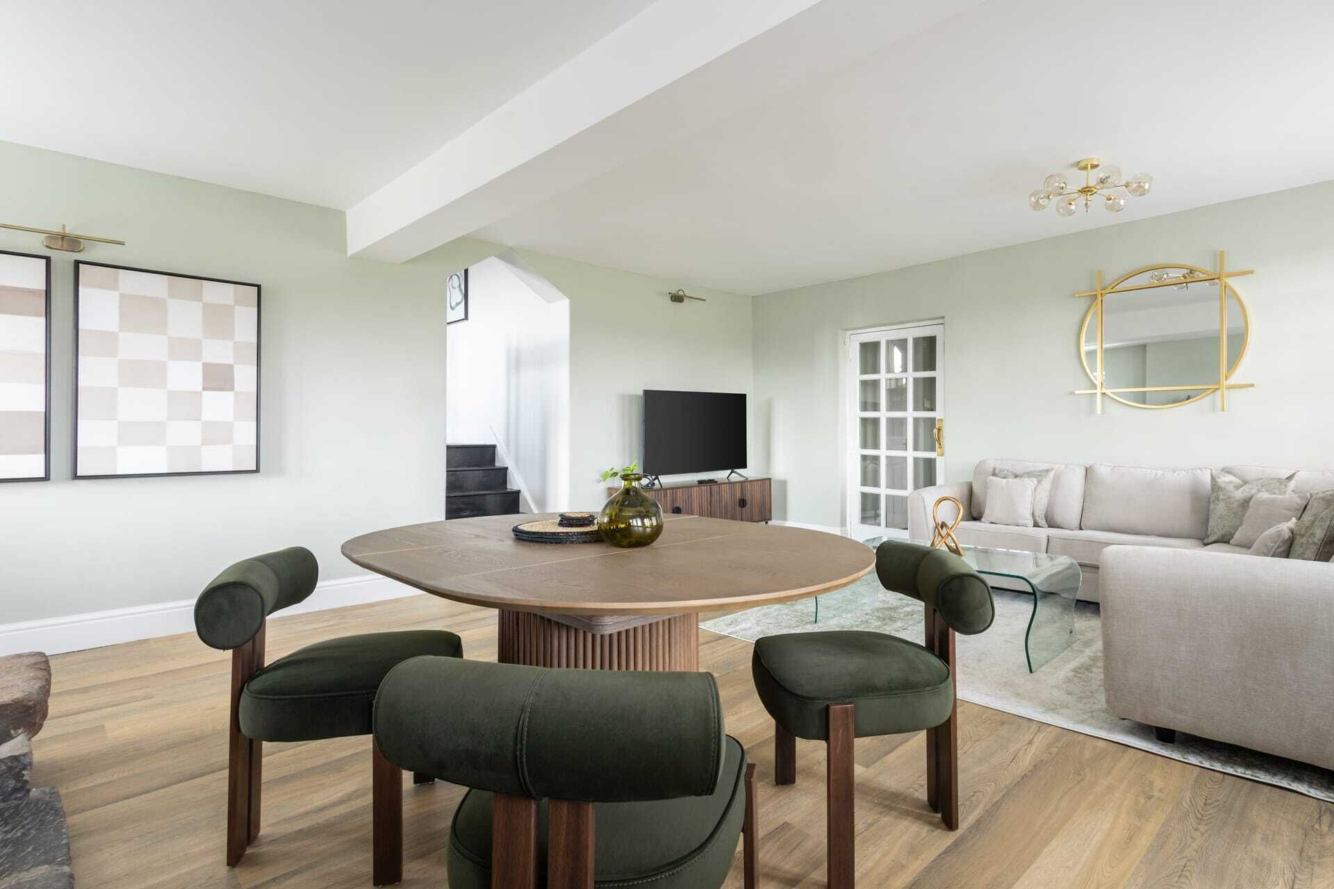 Een moderne woonkamer met een ronde tafel, vier stoelen, een bank en een televisie.