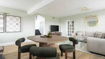 Een moderne woonkamer met een ronde tafel, vier stoelen, een bank en een televisie.