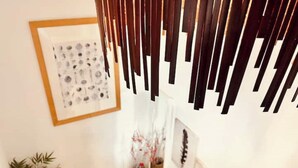 Una escalera con barandilla de madera, una obra de arte abstracto enmarcada en la pared y una planta en maceta.