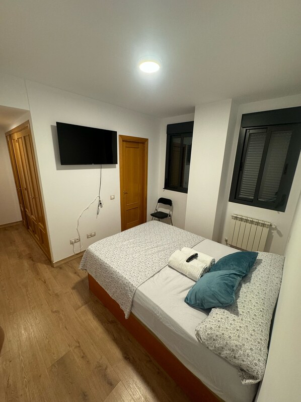 A bedroom with a bed, a TV mounted on the wall, a window, and a radiator. - Mars Suites Zapata  (Madrid)