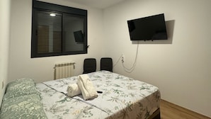 A bedroom with a bed, a window with blinds, a wall-mounted TV, and a radiator. - Mars Suites Zapata  (Madrid)
