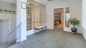 A hallway with a wooden bench, a potted plant, and a framed certificate on the wall.