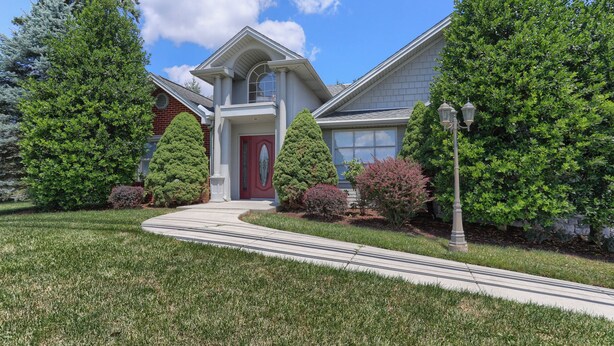A two-story house with a red door, a covered front porch, and a driveway leading to the entrance.