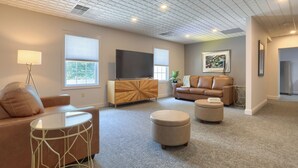A modern living room with a sofa, ottoman, and a TV on a wooden cabinet.