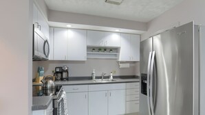 A modern kitchen with white cabinets, stainless steel appliances, and a built-in oven.
