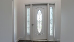 A white door with a decorative glass panel and a textured carpeted floor.