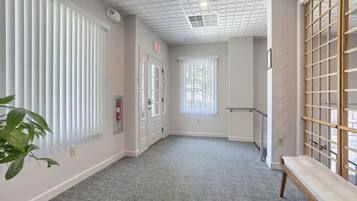 A hallway with a bench, a wooden screen, and a door with an exit sign.