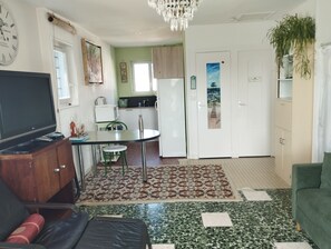 A compact living space with a dining area, kitchenette, and a television.
