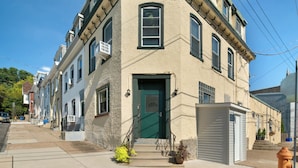 A corner building with a green door, multiple windows, and a small porch area. - Walk to Main St! Spacious 2BR Bi-Level • Sleeps 8 (Philadelphia)