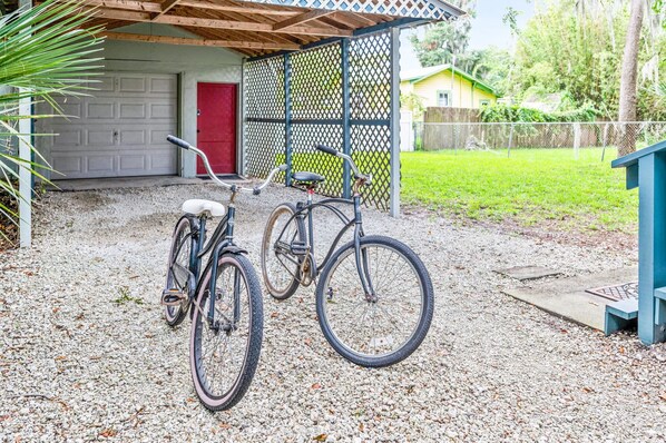 A gravel driveway with two bicycles parked in front of a house with a red door and a garage.