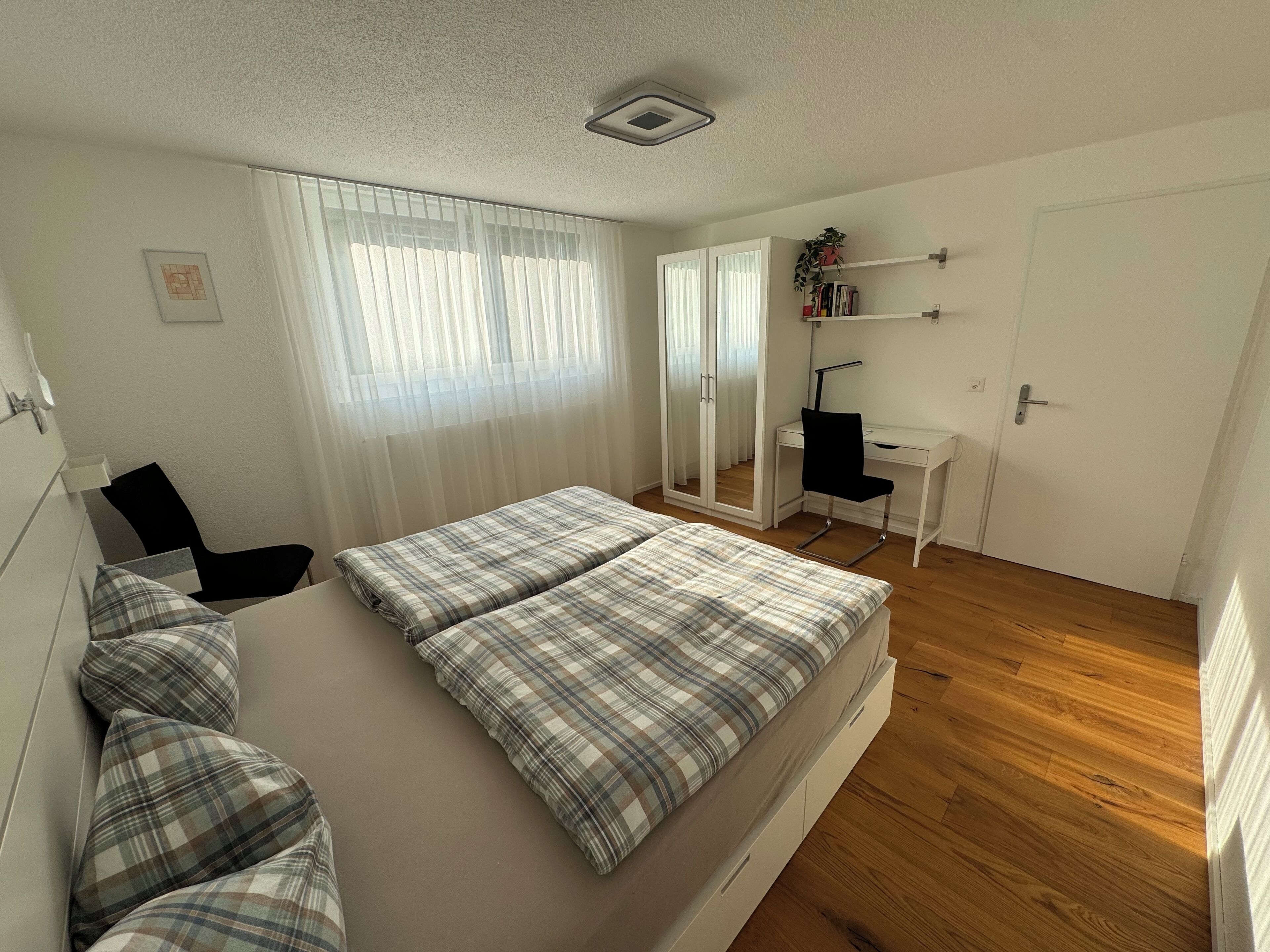 A bedroom with a bed, a desk, and a chair.