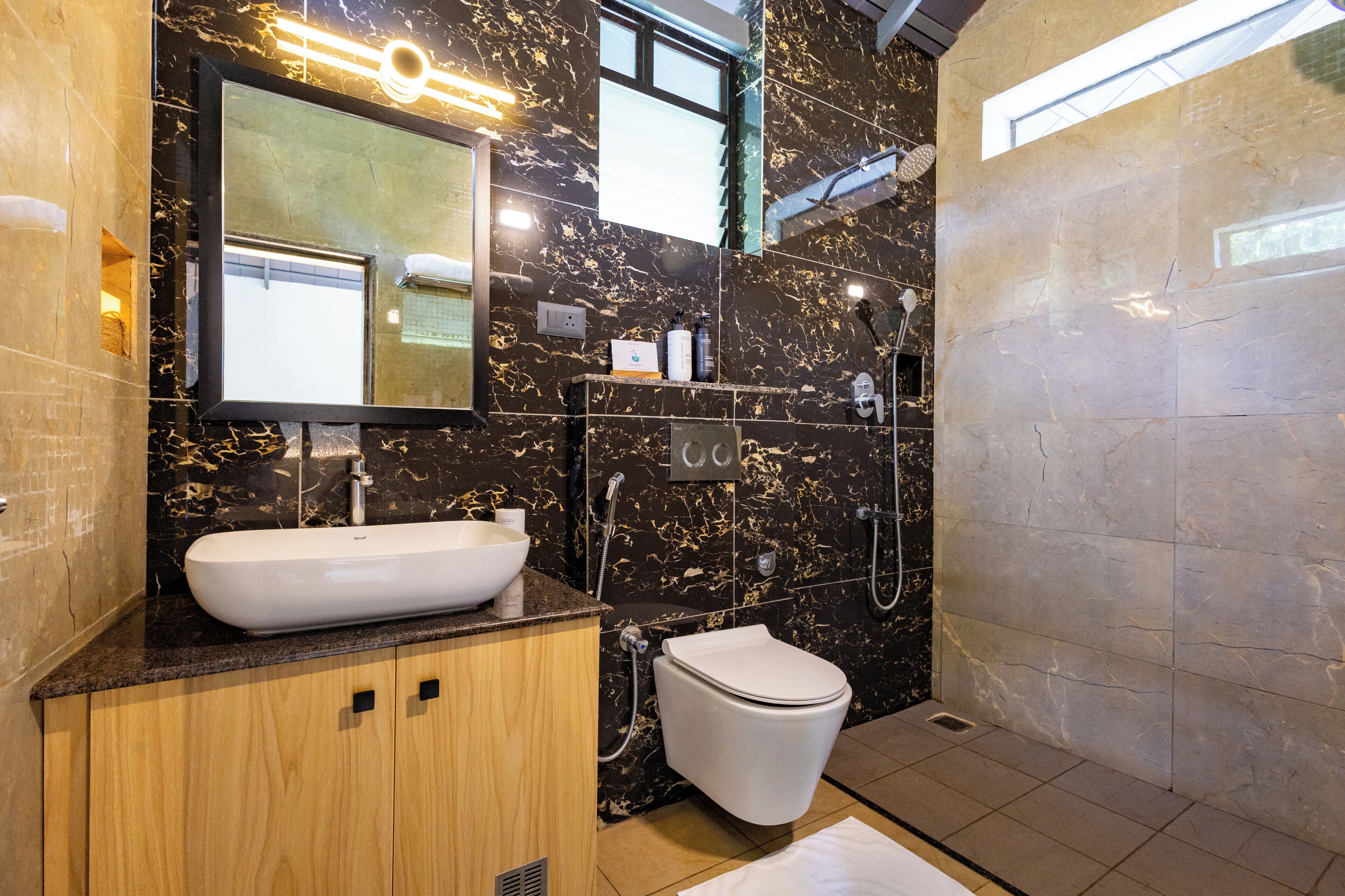 A modern bathroom with a marble sink, a toilet, a shower, and a large mirror.
