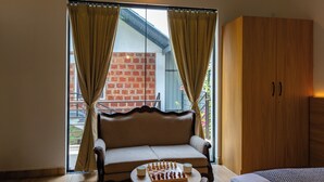 A room with a sofa, a chessboard, and a wooden wardrobe. - Avocado Cottages by Alaya stays (Somvarpet)