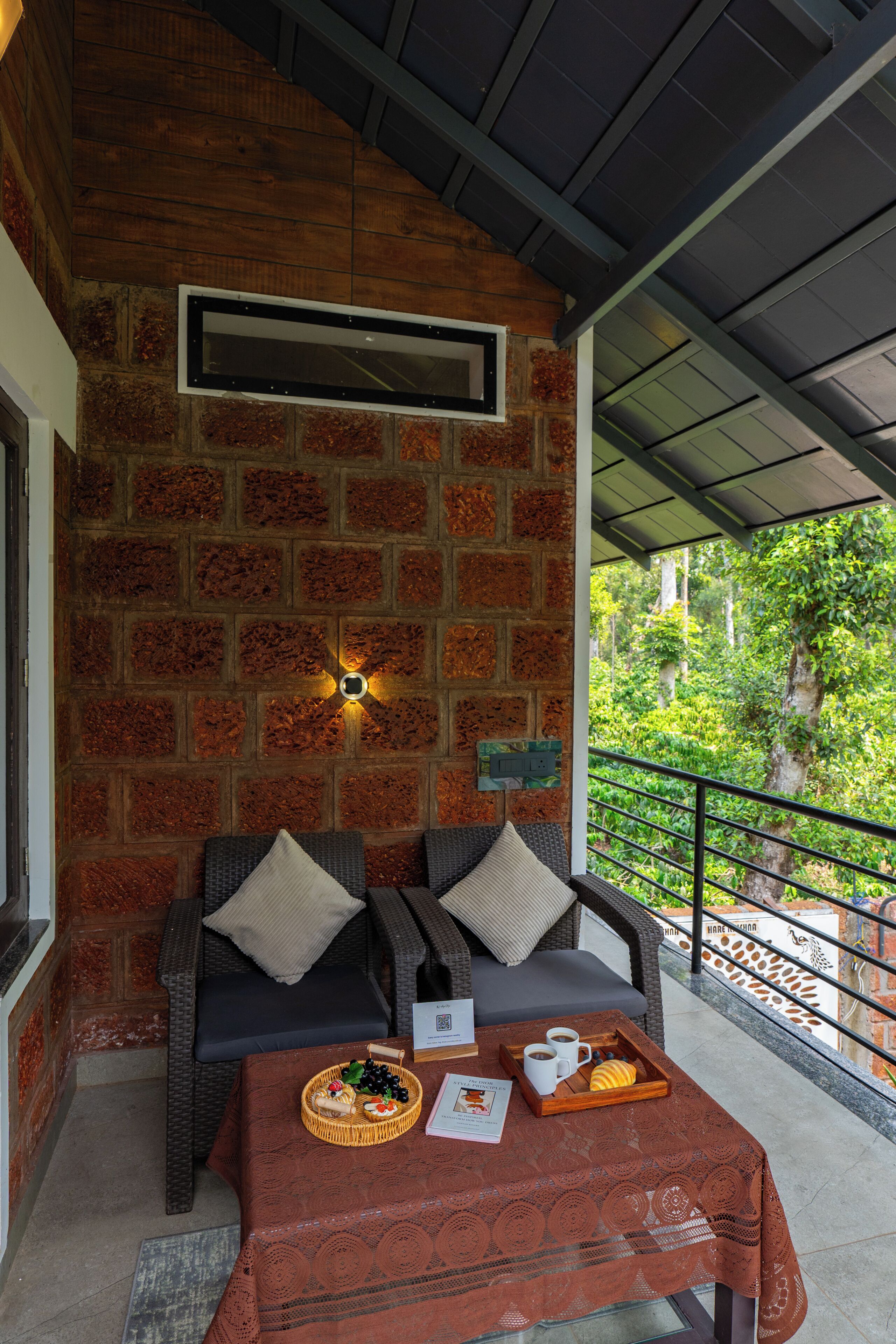 Un rincón acogedor con pared de ladrillo, una mesa con una cesta de aperitivos y vistas al verdor.