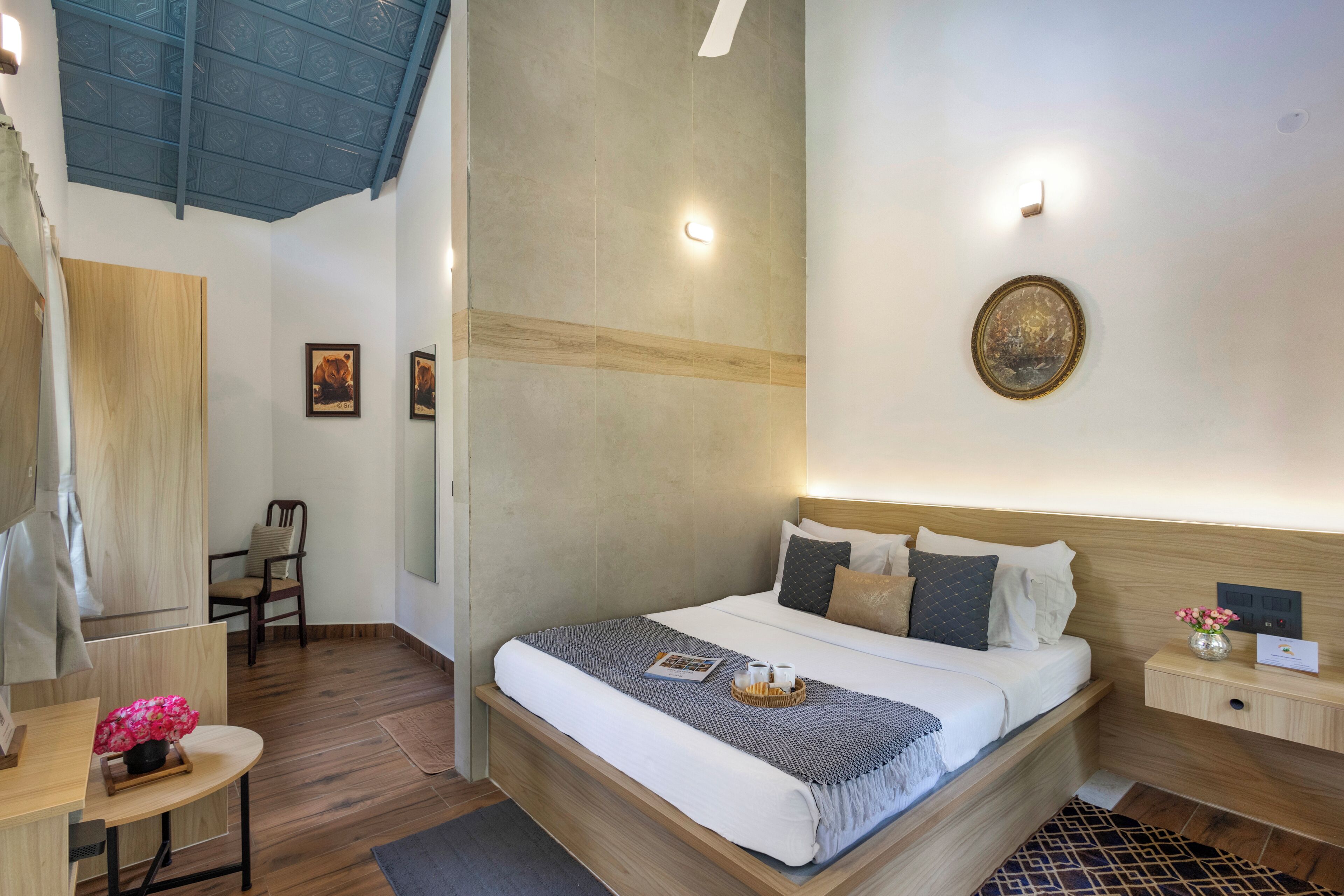 A hotel room with a bed, bedside table, chair, and a desk with a chair.