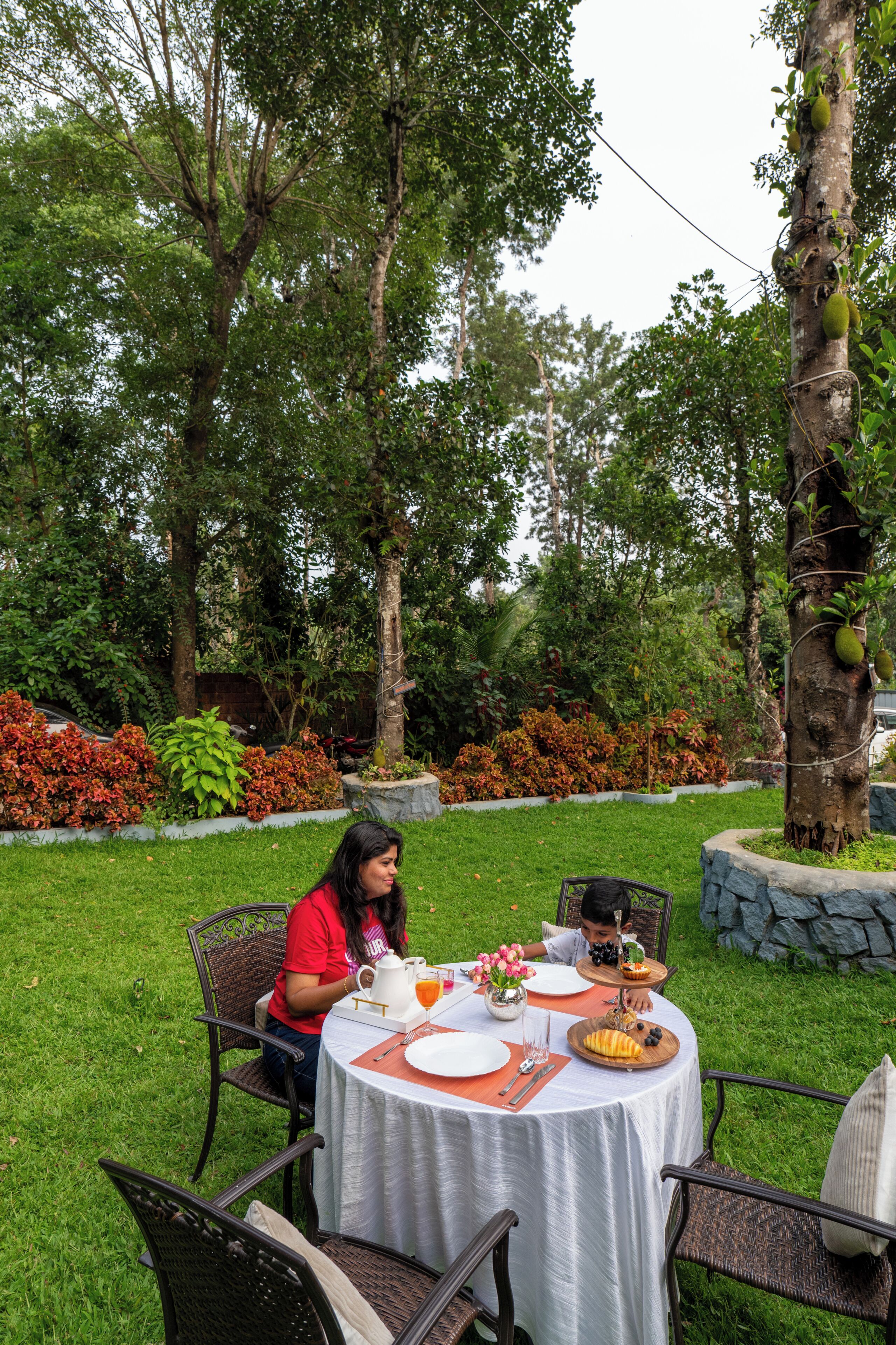 Uma área de refeições ao ar livre com mesa redonda, cadeiras e ambiente de jardim.