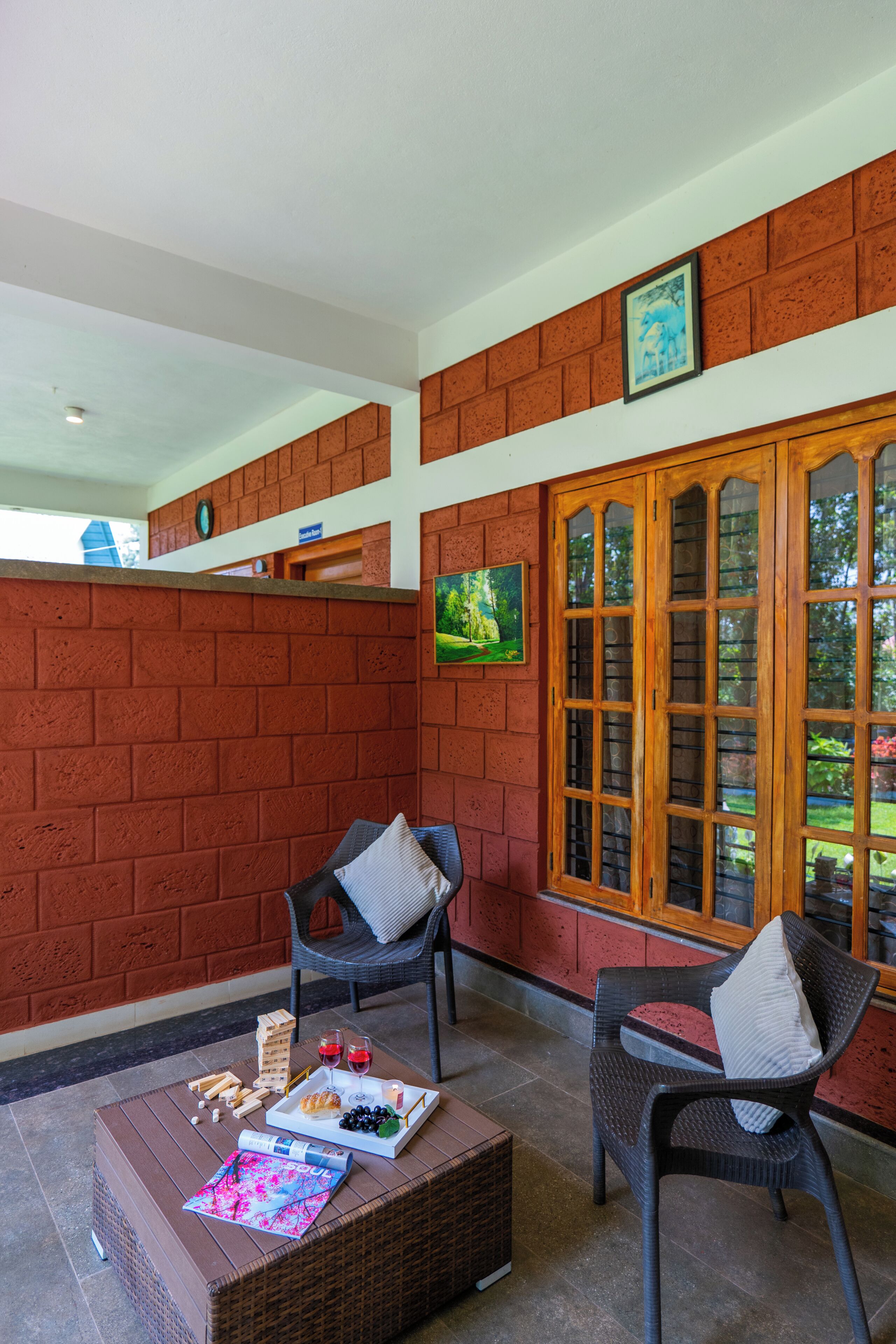 Una habitación con pared de ladrillo, ventana con marco de madera, mobiliario de mimbre y una mesa con aperitivos y bebidas.