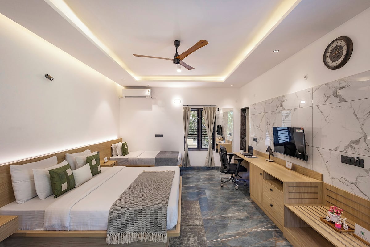 A modern hotel room with a large bed, a desk, a TV, and a ceiling fan.