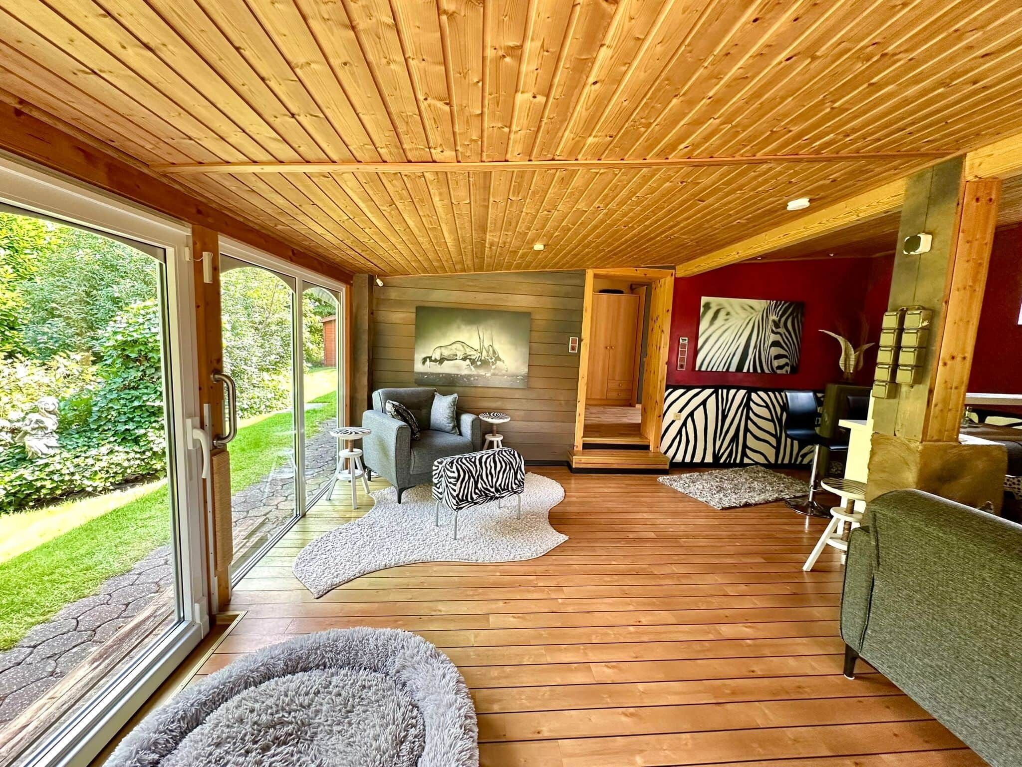 Ein modernes Interieur mit Holzböden, einem Sofa, einem Hocker mit ZEBRA-Muster und einem Bild an der Wand.