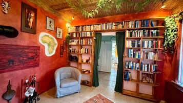 Ein gemütliches Zimmer mit Bücherregal, einem Sessel und einer Karte an der Wand.