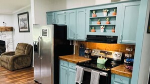 Una cocina con alacenas azul claro, un refrigerador de acero inoxidable, una estufa y piso de madera.