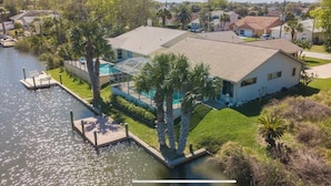 A house with a dock, surrounded by water and greenery.