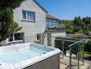 Una casa con jacuzzi, un balcón con plantas en macetas y vistas a un paisaje verde.