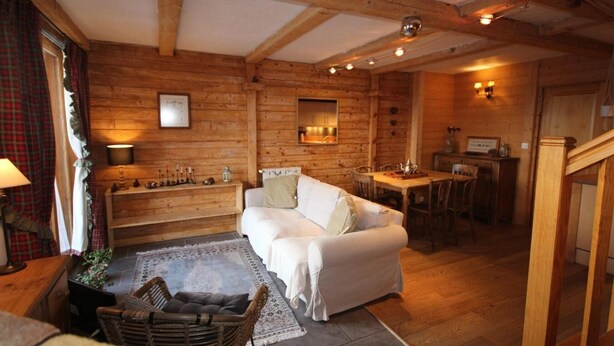 A cozy log cabin interior with a white sofa, wooden dining table, and a fireplace. - 50m from ski slopes, 1st floor, terrace, fireplace or stove, tv, 72m², Les Saisies (Hauteluce)