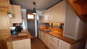 A modern kitchen with wooden cabinets, a stainless steel sink, and a hanging plant. - 50m from ski slopes, 1st floor, terrace, fireplace or stove, tv, 72m², Les Saisies (Hauteluce)