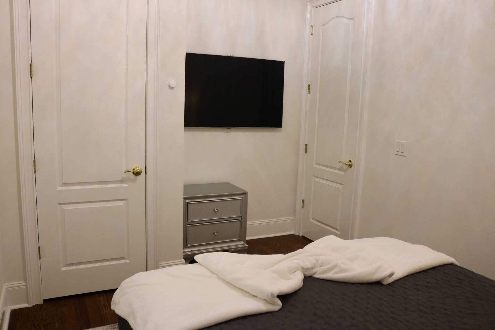 Une chambre à coucher avec un lit, une commode et un téléviseur fixé au mur.