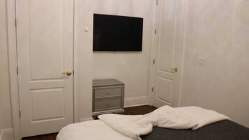 Une chambre à coucher avec un lit, une commode et un téléviseur fixé au mur.