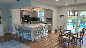 Una cocina moderna con una isla central, taburetes de bar y una mesa de comedor con sillas.