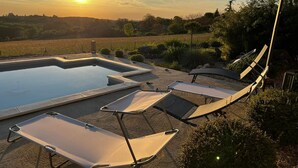 Un espace piscine avec des chaises longues et une vue sur le coucher de soleil.
