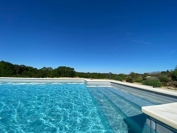 Relax by the expansive pool surrounded by lush greenery and trees.